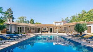 A swimming pool with lounge chairs, a covered patio, and a building with a tiled roof. - Large Villa with Private Pool, Balcony and Wi-Fi in Saint-Georges des Coteaux (Saint-Georges-des-Coteaux)