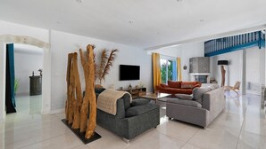 A modern living room with a sofa, a coffee table, and a TV. - Large Villa with Private Pool, Balcony and Wi-Fi in Saint-Georges des Coteaux (Saint-Georges-des-Coteaux)