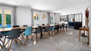 A modern dining area with a long table, chairs, and a view of the outdoors. - Large Villa with Private Pool, Balcony and Wi-Fi in Saint-Georges des Coteaux (Saint-Georges-des-Coteaux)