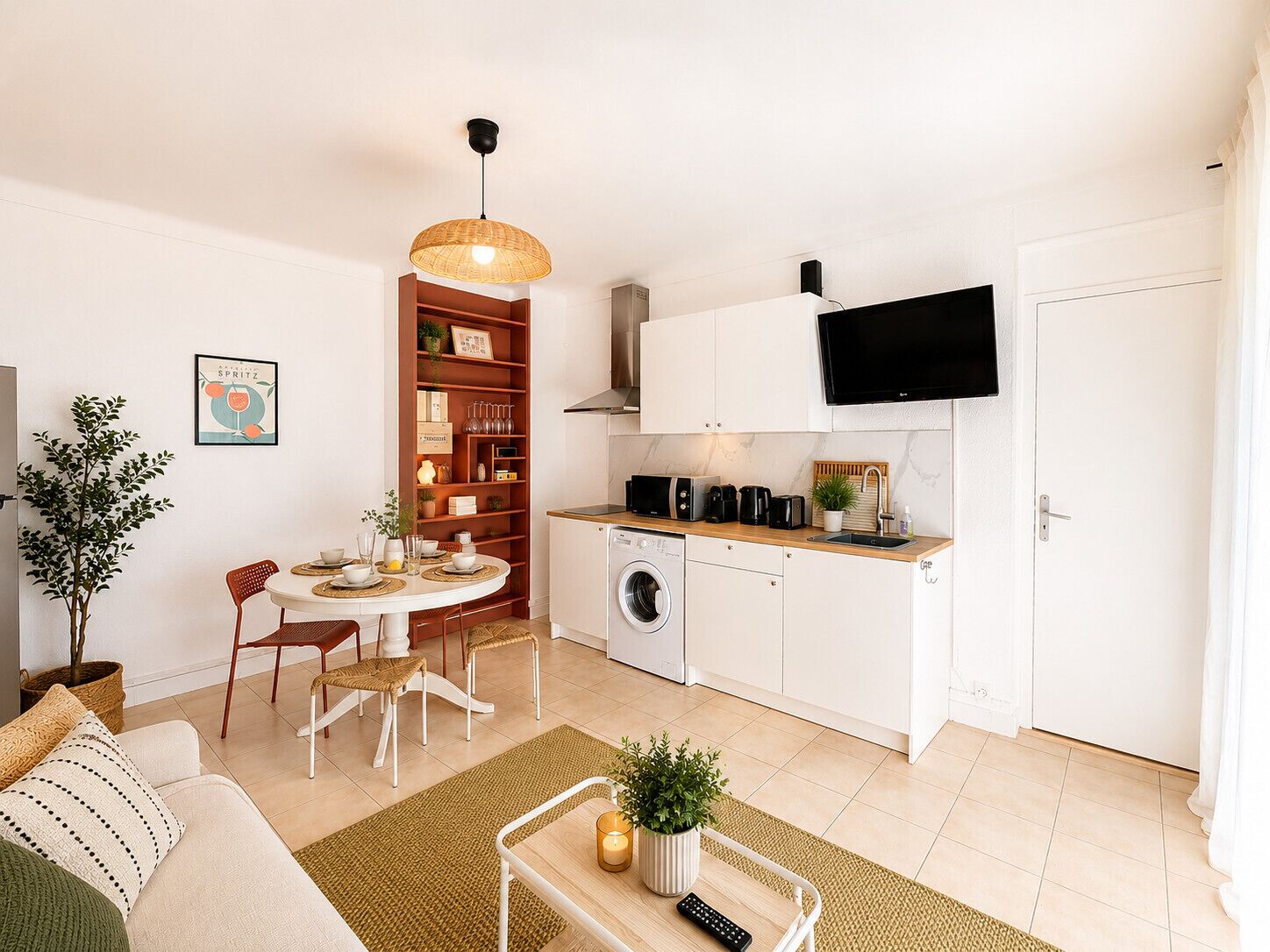 Un espace de vie compact comprenant un coin repas, une cuisine et un téléviseur fixé au-dessus du comptoir.