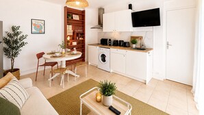 Um espaço compacto com área de refeições, cozinha e televisão fixada acima do balcão.