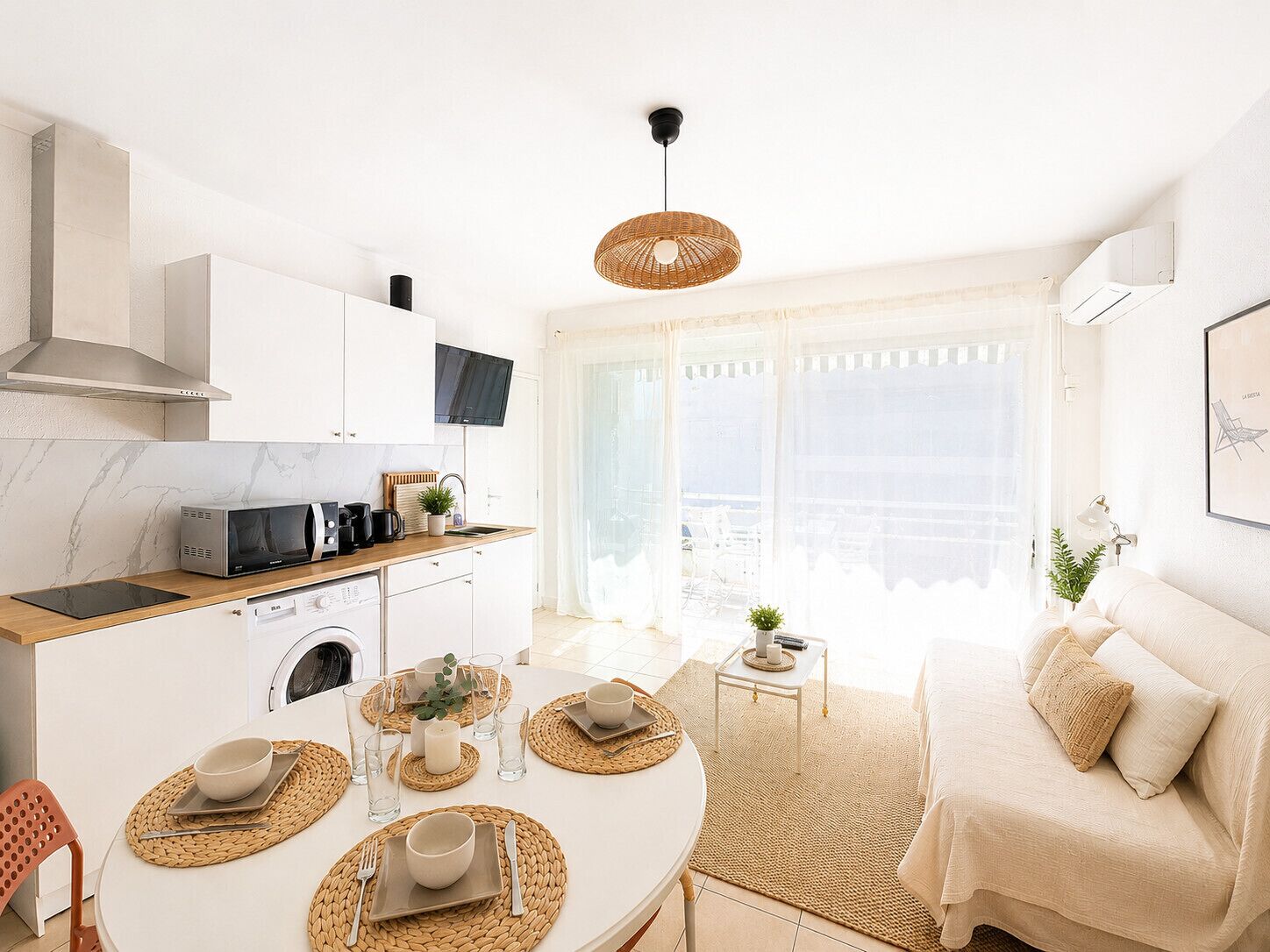 A modern kitchen with a dining area, a sofa, and a view of the city.