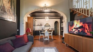 A living room with a sofa, a TV, and a fireplace. - Elegant Penthouse in the heart of Santo Spirito (Firenze)