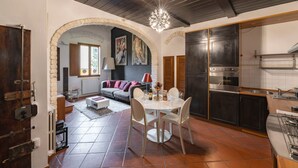 A kitchen with a dining area, a fireplace, and a stone archway leading to a living room. - Elegant Penthouse in the heart of Santo Spirito (Firenze)