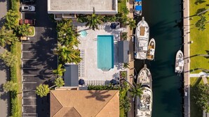 An aerial view of a resort with a swimming pool, docked boats, and a parking area. - Spacious 2-Bedroom Suite Just Steps from Famous Fort Lauderdale Beach (Fort Lauderdale)