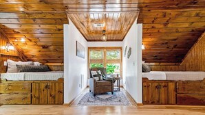 A cabin with a loft bedroom, a cozy seating area, and a view of greenery outside. - Charming Waterfront Retreat. deep-water dock (Gainesville)