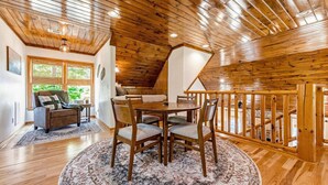 A cozy interior with a wooden ceiling, a dining area with a round table and chairs, a sofa, and a staircase with a wooden railing. - Charming Waterfront Retreat. deep-water dock (Gainesville)