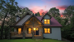 A two-story house with a porch, a stone pathway leading to the entrance, and a view of the surrounding trees. - Charming Waterfront Retreat. deep-water dock (Gainesville)