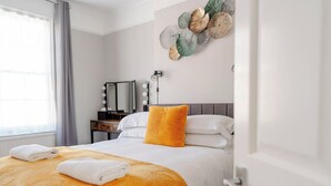 A hotel room with a bed, a vanity with a mirror and lights, and a wall decoration. - Luxury Victorian Terrace Inside City Walls (York)