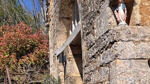 Une structure en pierre surmontée d’une statue, avec un escalier en bois et une rambarde en métal.
