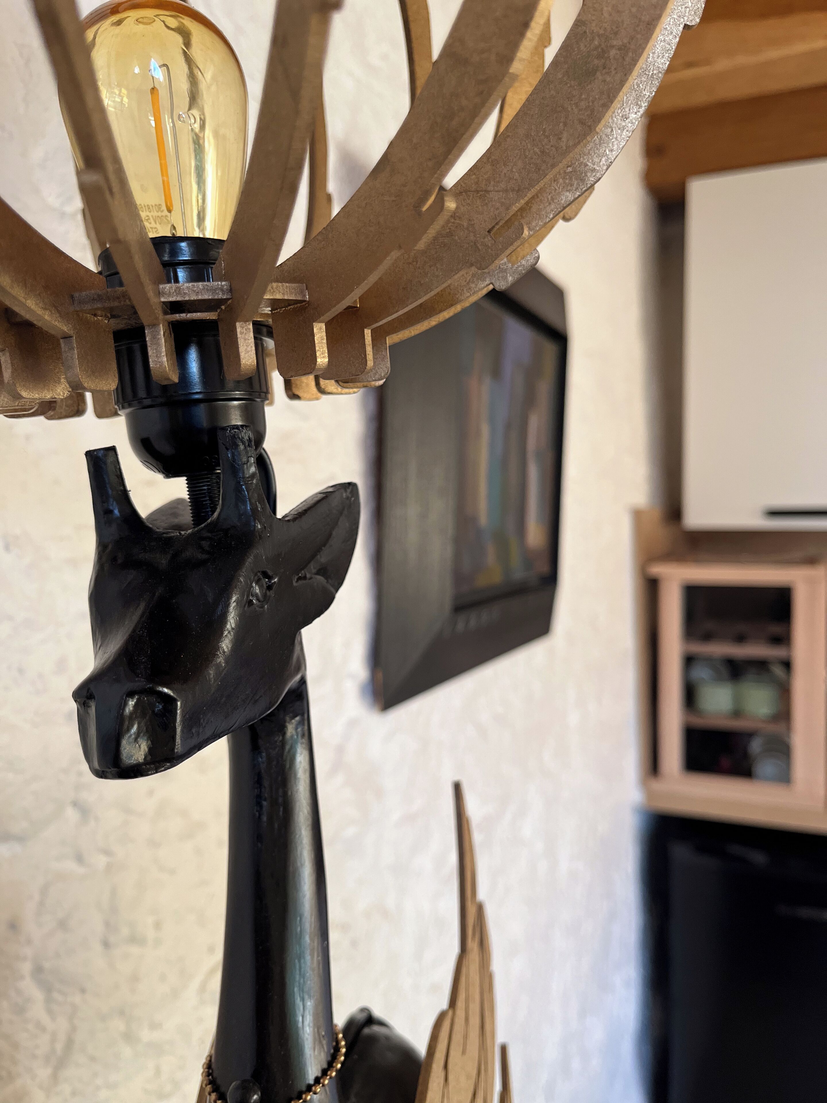 Un candelabro con una bombilla, una base de metal negro y un elemento decorativo de madera.