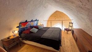 Une chambre à coucher avec un plafond en arc, un lit, une table de chevet, une lampe et une chaise.