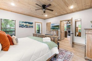 Une chambre à coucher avec un lit, un ventilateur de plafond, une télévision et une vue sur l’extérieur.