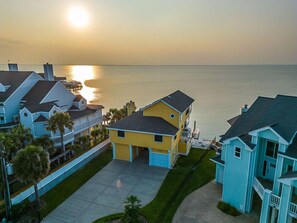 A coastal residential area with houses, a clear sky, and a sunset over the water. - Stunning Bayfront Home!  Panoramic Views, Fishing, Crabbing and Epic Sunsets. (Jamaica Beach)