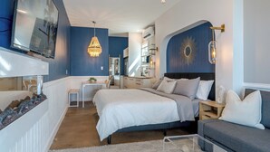 A bedroom with a bed, bedside tables, a desk, a chair, a chandelier, and a wall-mounted TV. - Stunning Bayfront Home!  Panoramic Views, Fishing, Crabbing and Epic Sunsets. (Jamaica Beach)