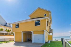 Um edifício residencial de dois andares com garagem, varanda e vista para o mar.
