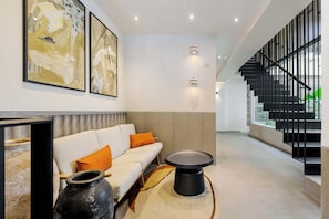 Een modern interieur met een bank, een ronde tafel en een trap.