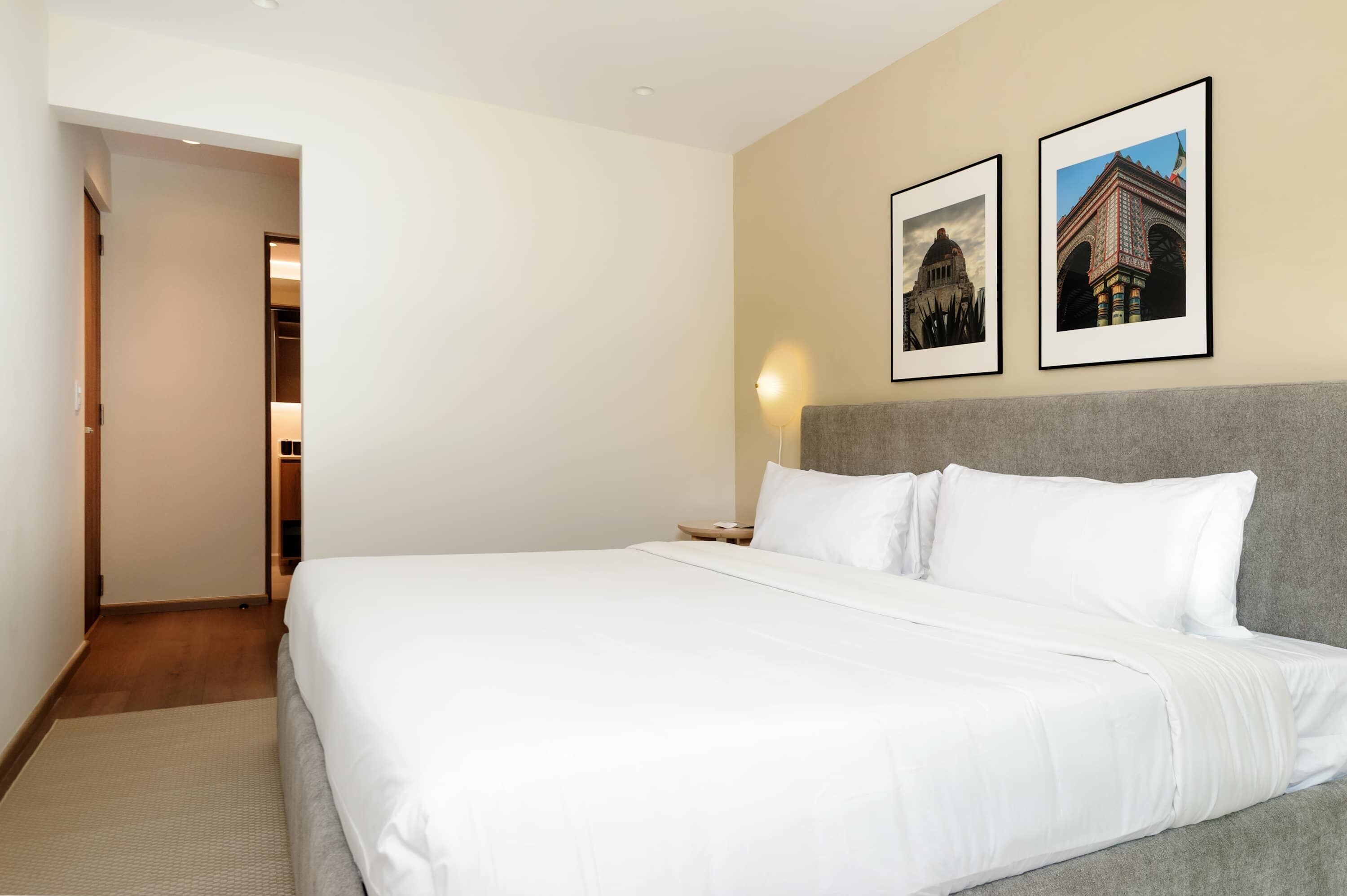 Una camera d'albergo con un letto grande, un comodino e due quadri appesi al muro.