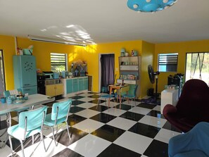 A room with a checkered floor, a kitchen area with a fridge, microwave, and cabinets, and a dining area with a table and chairs. - Calm & Cosy Island House • Short Walk to an Idyllic, Empty Beach (The Forest)
