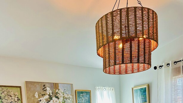 A bedroom with a bed, a hanging wicker light fixture, and floral wall art. - Serene 3-bedroom townhome in charming Lompoc perfect for families (Lompoc)