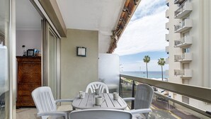 Ein Balkon mit Tisch und Stühlen, Blick auf die Straße, und ein Gebäude mit Balkonen.