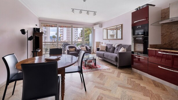 Ein modernes Apartment mit Essbereich, Sofa, Küche und großen Fenstern.