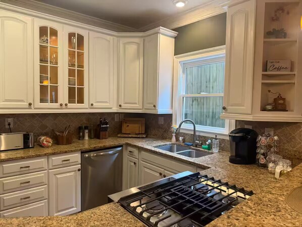 A kitchen with white cabinets, a gas stove, a dishwasher, and a coffee maker. - Walkable Neighborhood • King Bed • Near Downtown (Atlanta)