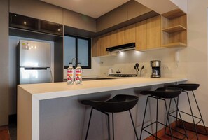 Eine moderne Küche mit einem integrierten Kühlschrank, einer Kaffeemaschine und Barhocker.