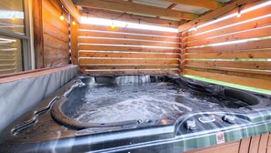 Een hottub in een houten hutje met uitzicht op de omgeving.