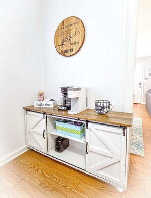 Eine Küchenzeile mit einer Kaffeebar, einer Kaffeemaschine, einer Kaffeemilchkaraffe und einem dekorativen Holzschild.