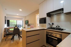 A modern kitchen with a gas stove, oven, and microwave. There is a dining area with a table and chairs. - w* | Comfort Living 2BR w/ Balcony in San Isidro (San Isidro)