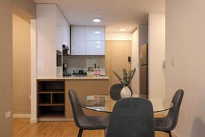 A modern kitchen with white cabinets, a glass dining table, and two chairs. - w* | Comfortable Living 2BR w/ Balcony in San Isidro (San Isidro)