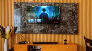 A television mounted on a wall displaying the Netflix series 'Money Heist.'