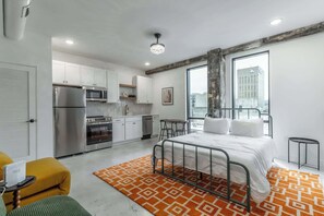 Eine moderne Wohnung mit Küche, einem Bett und Blick auf die Stadt.