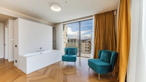 A modern bathroom with a large bathtub, two teal armchairs, and a large window with a city view. - All Inclusive stay by PS - Durres Bay  (Rrashbull)