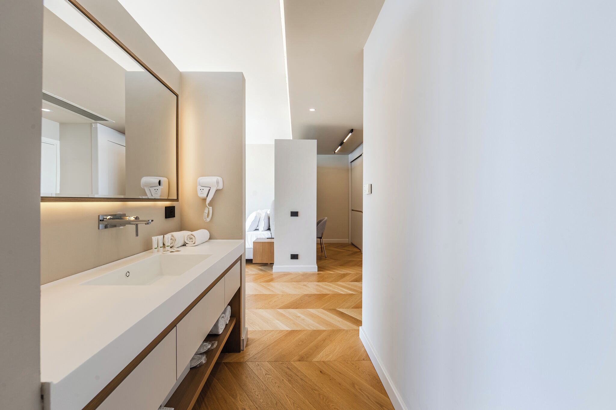 A modern bathroom with a large mirror, white sink, and towel rack.
