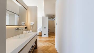 A modern bathroom with a large mirror, white sink, and towel rack.
