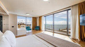 A modern hotel room with a large bed, a balcony with a view, and a separate seating area with chairs. - All Inclusive stay by PS - Durres Bay  (Rrashbull)