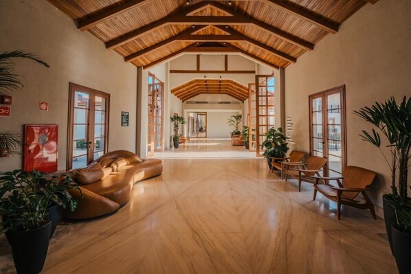 A spacious interior with a high ceiling, wooden beams, and a central open area with seating. - Pyrineus Resort Apartments (Pirenópolis)