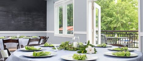 A dining area with round tables, white tablecloths, and green napkins.