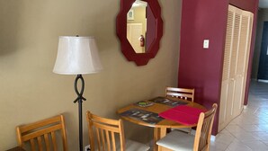 Un área de comedor con una mesa, sillas, una lámpara y un espejo en la pared.