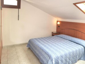 A bedroom with a bed, a nightstand, a wall-mounted light, and a window. - Bright Accommodation 30m From the Beach in Lignano (Lignano Sabbiadoro)