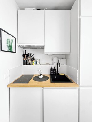 A compact kitchen with a black induction cooktop, a sink, and a coffee machine. - Studio, 18 m² • 3 min from the Champs-Élysées & the metro (Paris)