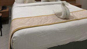 A hotel room with a large bed, two wall-mounted lamps, and a decorative wall.