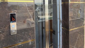 A marble elevator with a glass door, a digital display, and a sign above the door.