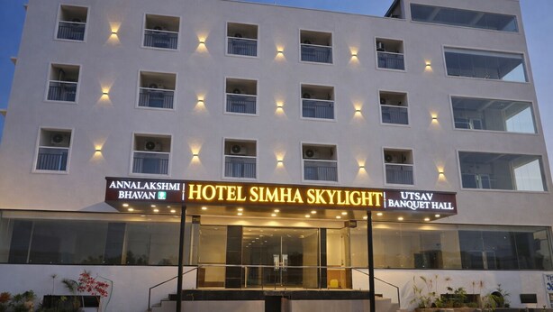 A multi-story hotel with balconies, a visible entrance, and signage for 'Hotel Simha Skylight' and 'Utsav Banquet Hall'.