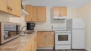 A kitchen with wooden cabinets, a stove, a refrigerator, and a microwave. - Tranquil poolside retreat!  Basement with 2 rooms! Close to Niagara Falls. (Niagara Falls)