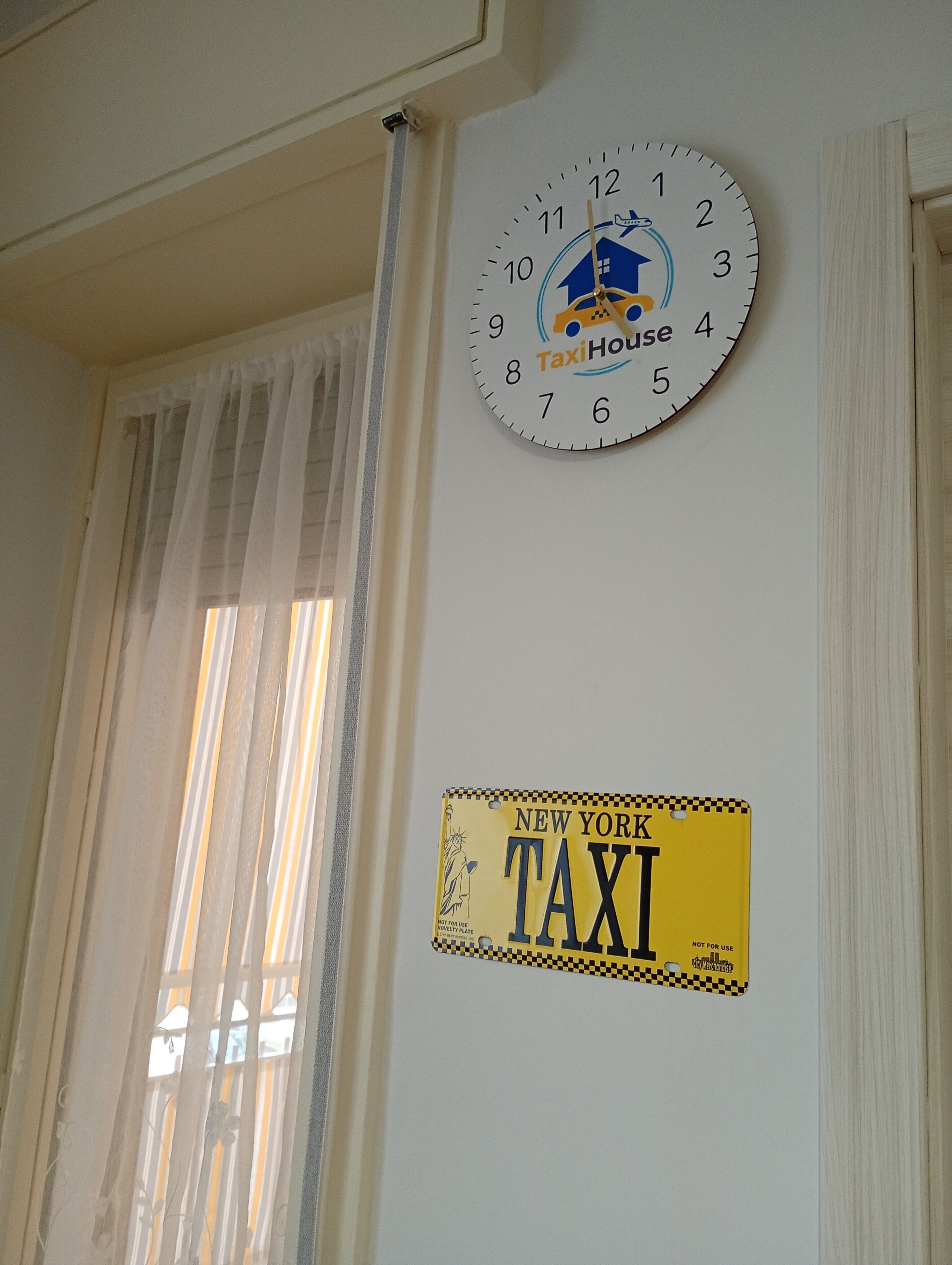 En väggklocka med texten ”TaxiHouse” och en registreringsskylt från en New York-taxi.