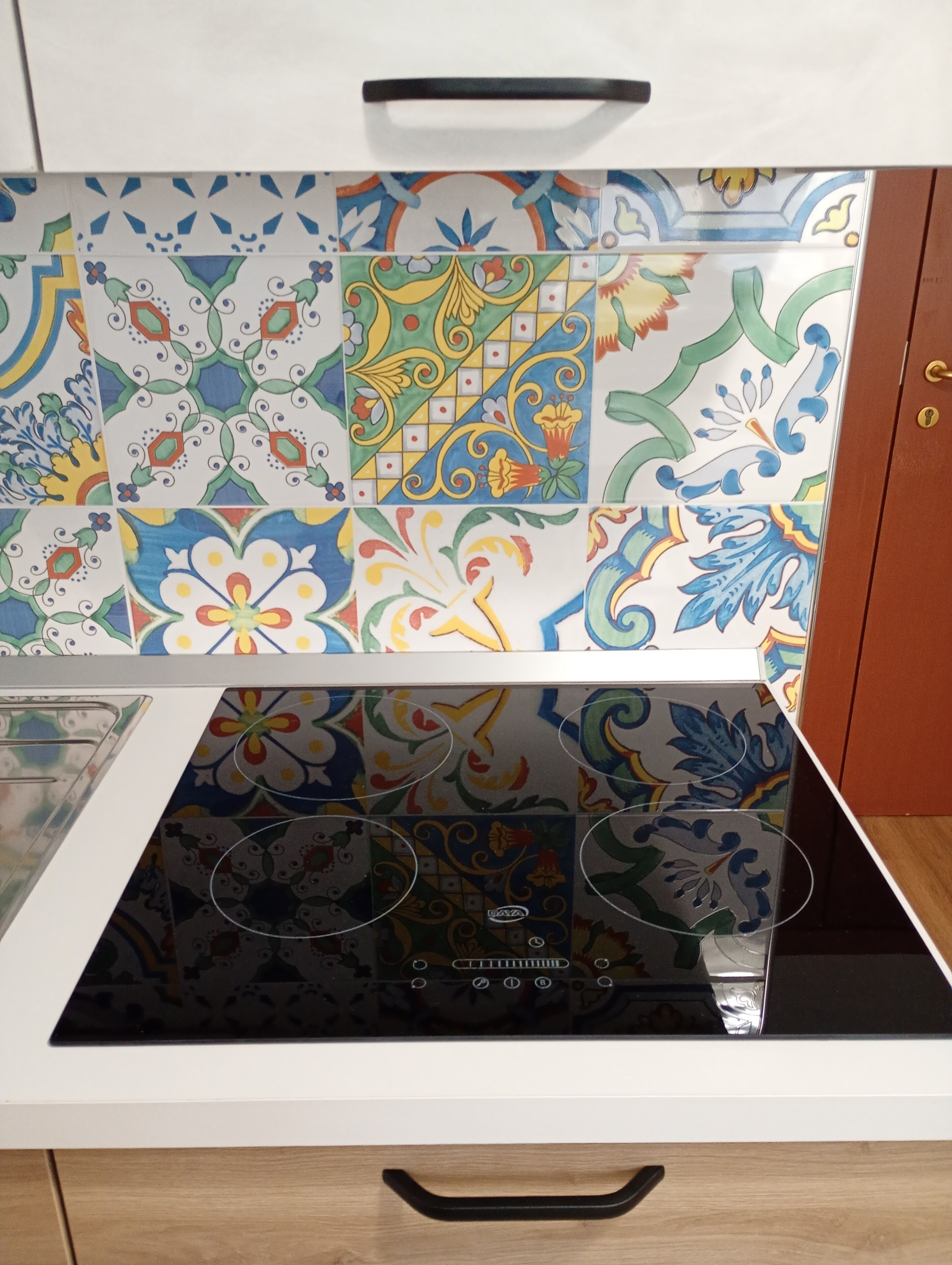Cozinha com fogão, micro-ondas e armário com azulejos coloridos.