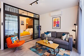 A modern hotel room with a sofa, a small table with a bottle, a chair, and a bed with a view. - LUNARIS - next to Yumbo, new and modern (Maspalomas)